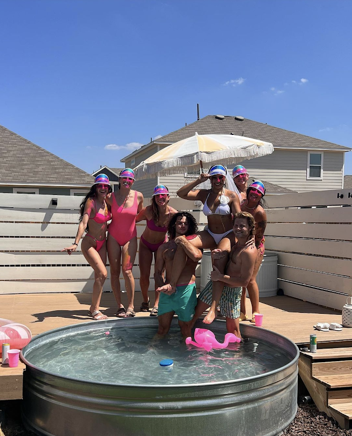 a group of people standing next to a swimming pool